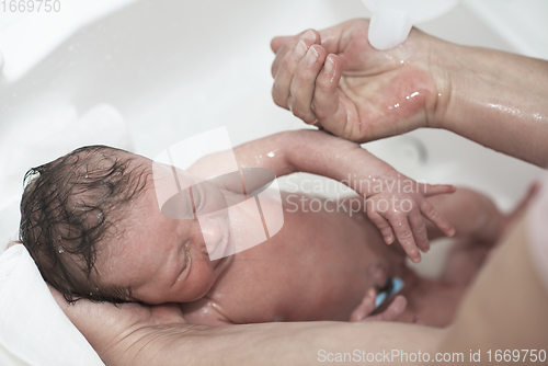 Image of Newborn baby girl taking a first bath