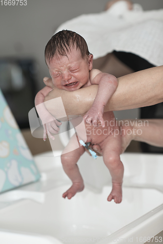 Image of Newborn baby girl taking a first bath