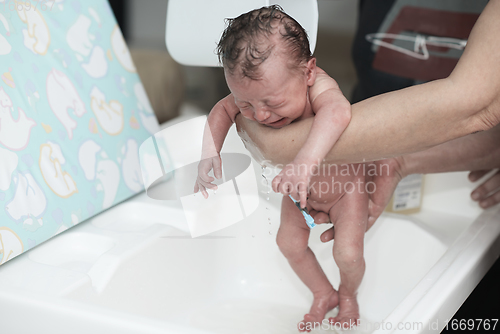 Image of Newborn baby girl taking a first bath