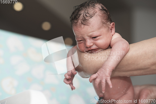 Image of Newborn baby girl taking a first bath