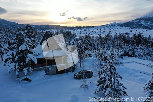 Image of fresh snow covered trees and wooden cabin in wilderness