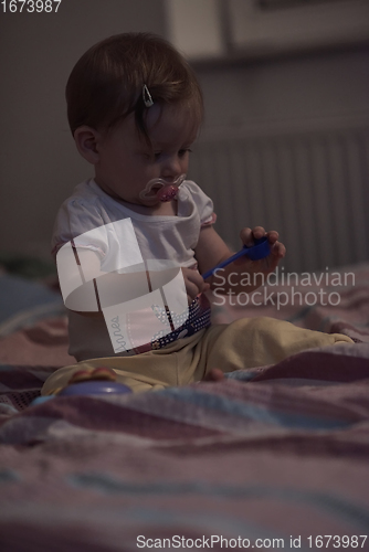 Image of cute little one year old baby and making first steps in bed