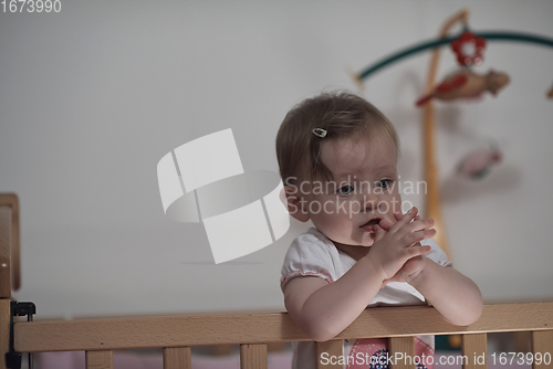 Image of cute little one year old baby and making first steps in bed