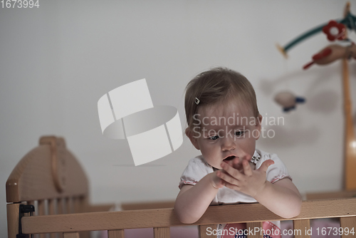 Image of cute little one year old baby and making first steps in bed