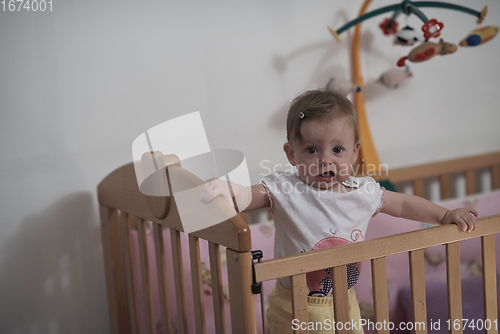 Image of cute little one year old baby and making first steps in bed