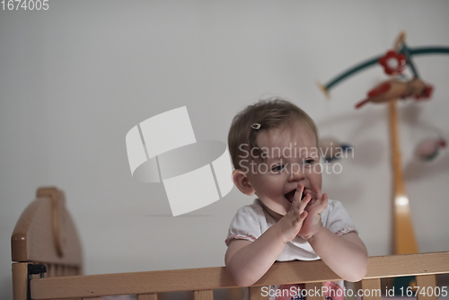 Image of cute little one year old baby and making first steps in bed