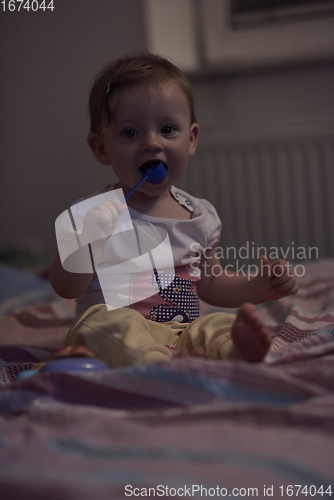 Image of cute little one year old baby and making first steps in bed