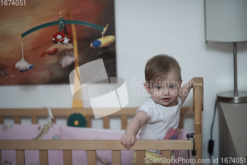 Image of cute little one year old baby and making first steps in bed