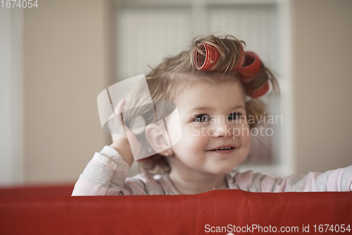 Image of little baby girl with strange hairstyle and curlers