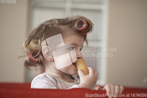 Image of little baby girl with strange hairstyle and curlers