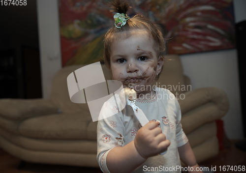 Image of baby girl eating her chocolate desert with a spoon and making a mess