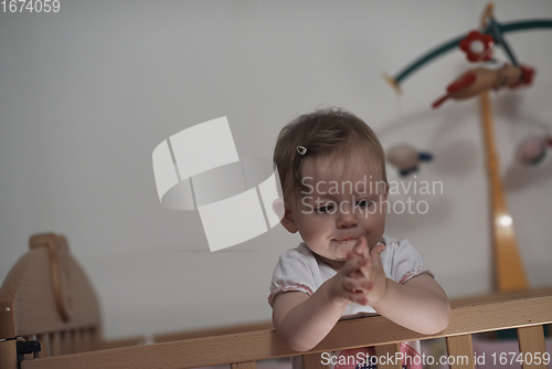 Image of cute little one year old baby and making first steps in bed