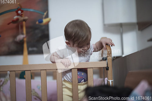 Image of cute little one year old baby and making first steps in bed