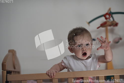 Image of cute little one year old baby and making first steps in bed
