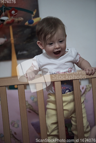 Image of cute little one year old baby and making first steps in bed