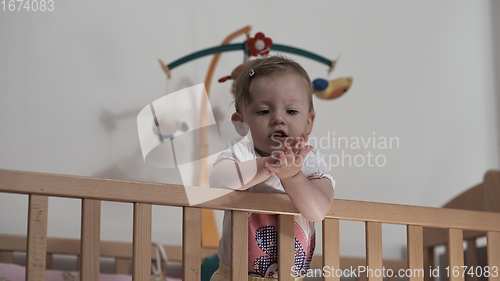 Image of cute little one year old baby and making first steps in bed