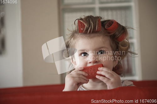 Image of little baby girl with strange hairstyle and curlers