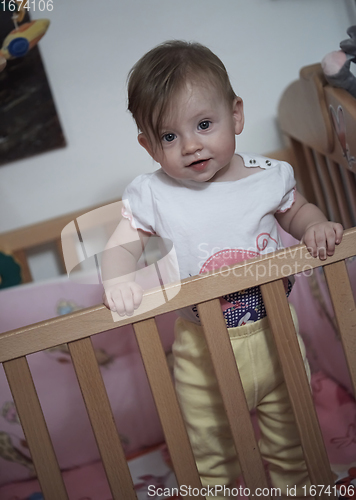 Image of cute little one year old baby and making first steps in bed