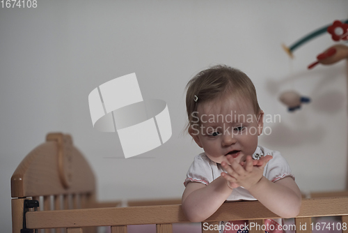 Image of cute little one year old baby and making first steps in bed