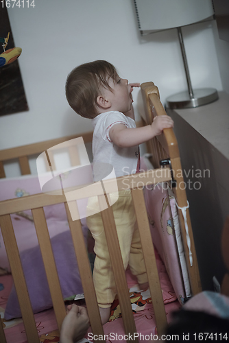 Image of cute little one year old baby and making first steps in bed