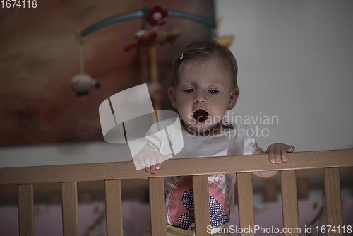 Image of cute little one year old baby and making first steps in bed