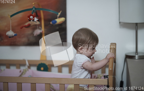 Image of cute little one year old baby and making first steps in bed