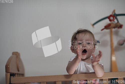 Image of cute little one year old baby and making first steps in bed