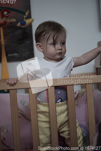 Image of cute little one year old baby and making first steps in bed