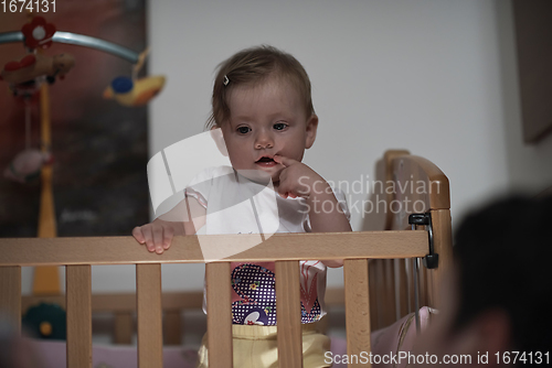 Image of cute little one year old baby and making first steps in bed