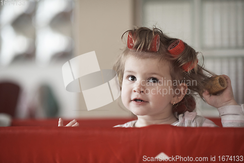 Image of little baby girl with strange hairstyle and curlers