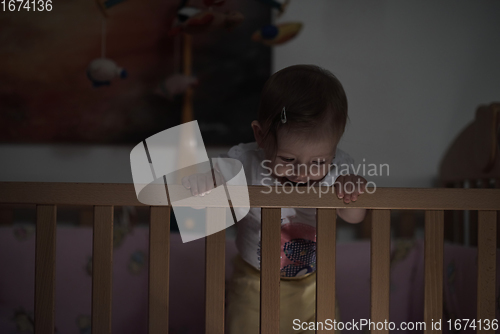 Image of cute little one year old baby and making first steps in bed