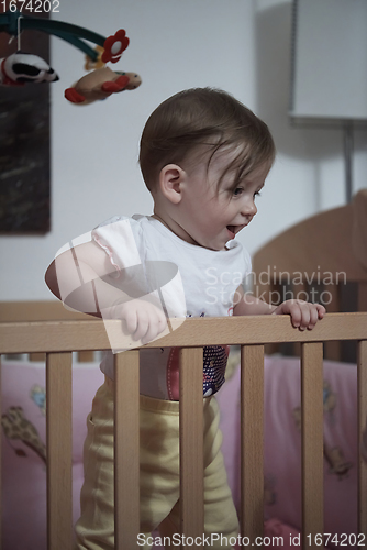 Image of cute little one year old baby and making first steps in bed