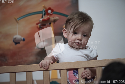 Image of cute little one year old baby and making first steps in bed