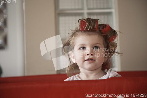 Image of little baby girl with strange hairstyle and curlers