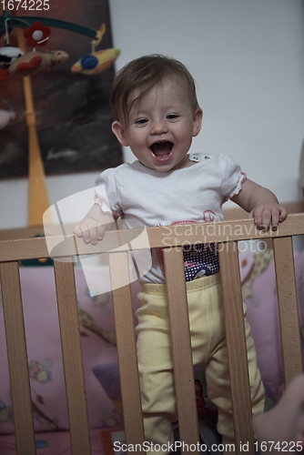 Image of cute little one year old baby and making first steps in bed