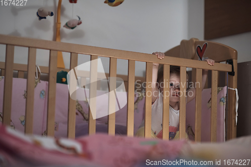 Image of cute little one year old baby and making first steps in bed