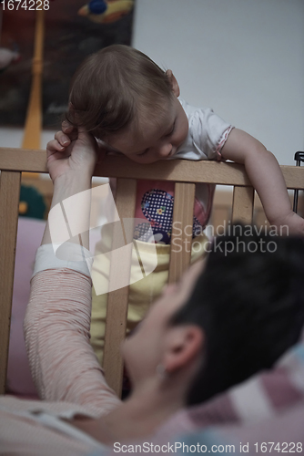 Image of cute little one year old baby and making first steps in bed