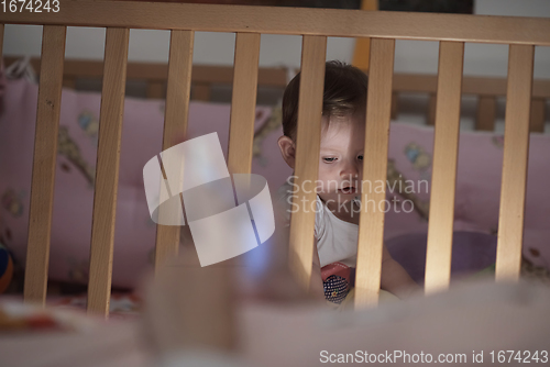 Image of cute little one year old baby and making first steps in bed