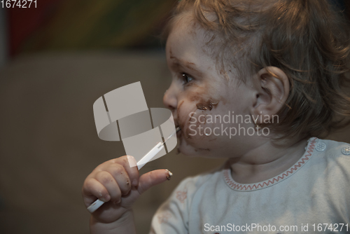 Image of baby girl eating her chocolate desert with a spoon and making a mess