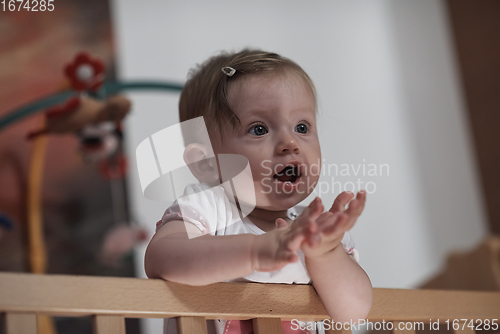 Image of cute little one year old baby and making first steps in bed