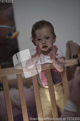 Image of cute little one year old baby and making first steps in bed