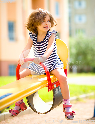 Image of Young happy girl is swinging in playground