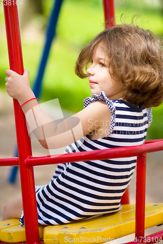 Image of Young happy girl is swinging in playground