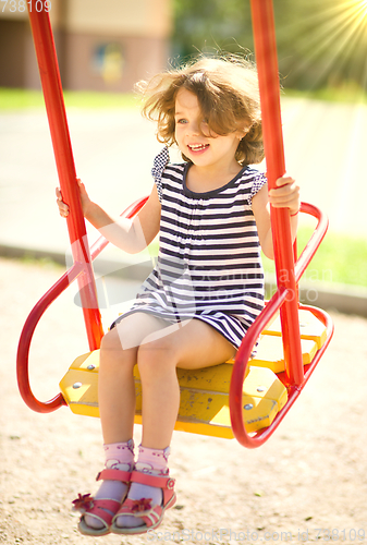 Image of Young happy girl is swinging in playground