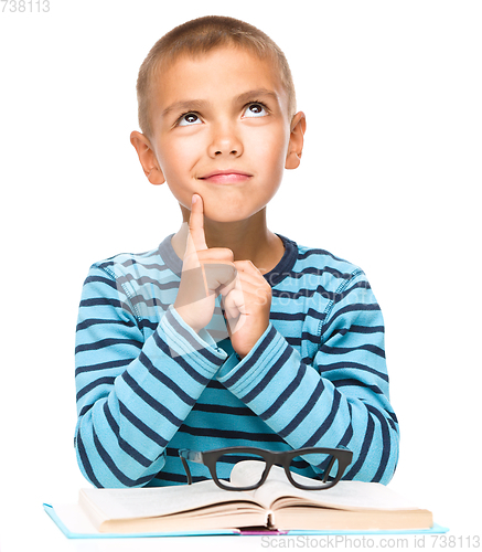 Image of Young boy is daydreaming while reading book