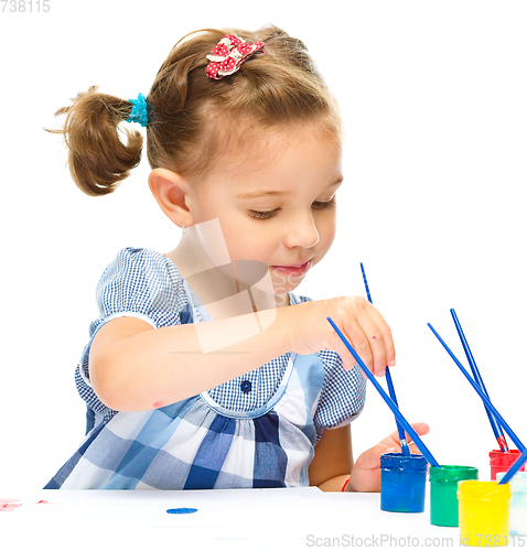 Image of Little girl is painting with gouache