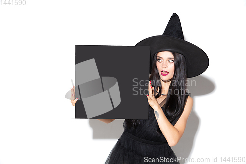 Image of Young woman in hat and dress as a witch on white background