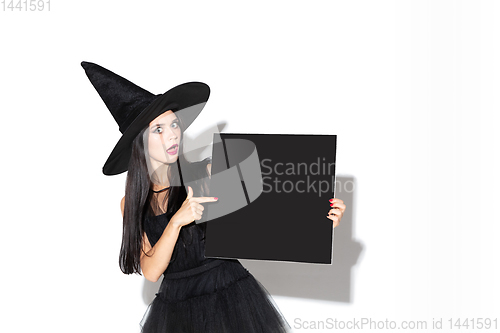 Image of Young woman in hat and dress as a witch on white background