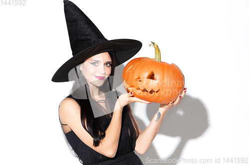 Image of Young woman in hat and dress as a witch on white background