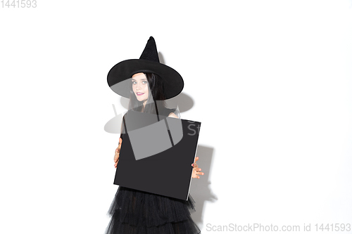 Image of Young woman in hat and dress as a witch on white background